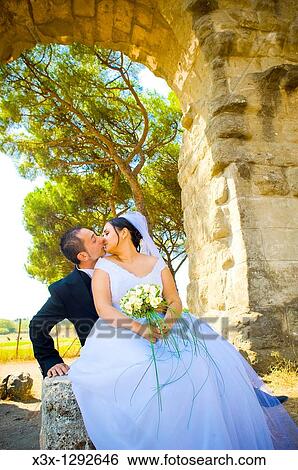 Bride and groom kissing among ancient ruins in Rome Italy View Large Photo Image Stock Photograph - Bride and groom kissing among ancient ruins in Rome Italy. Fotosearch