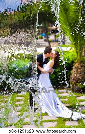Bride and groom kissing behind a water cascade View Large Photo Image Stock Photo - Bride and groom kissing behind a water cascade. Fotosearch