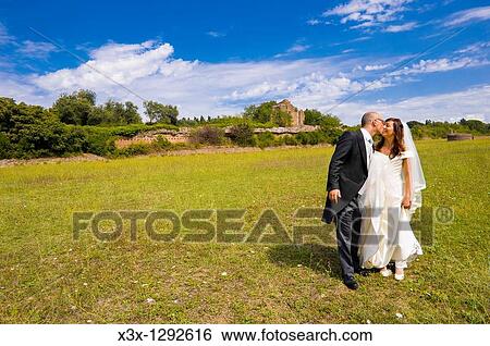 Bride and groom kissing in a park View Large Photo Image Stock Photograph - Bride and groom kissing in a park. Fotosearch