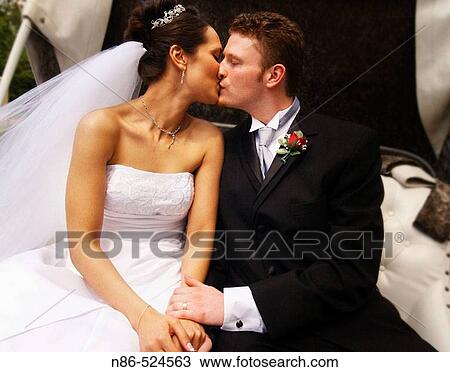 Stock Image - Bride and groom kissing in carriage. Fotosearch