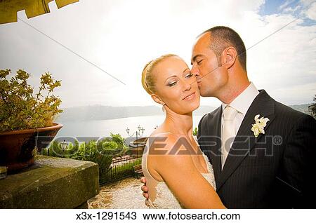 Stock Image - Bride and groom kissing in front of a Lake. Fotosearch