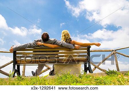 Bride and groom laying back on bench looking at the sky View Large Photo Image Stock Image - Bride and groom laying back on bench looking at the sky. Fotosearch