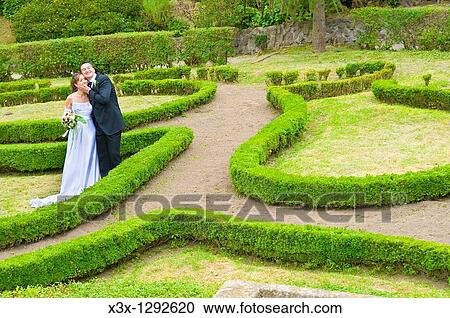 Stock Image - Bride and groom posing in a hedge park. Fotosearch