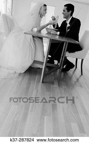 Bride and groom sharing a bowl of spaghetti sitting in new home with no furniture View Large Photo Image Picture - Bride and groom sharing a bowl of spaghetti sitting in new home with no furniture. Fotosearch