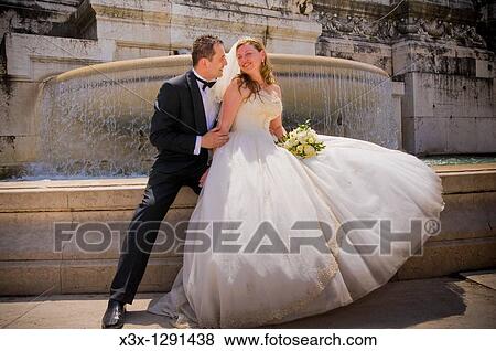 Bride and groom sitting in front of fountain in Rome, Italy View Large Photo Image Stock Photo - Bride and groom sitting in front of fountain in Rome, Italy. Fotosearch
