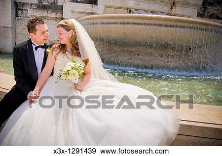 Stock Photo - Bride and groom sitting in front of fountain in Rome, Italy. Fotosearch