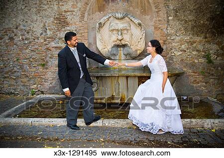 Stock Photography - Bride and groom standing near fountain in Piazza Illiria, Rome, Italy. Fotosearch
