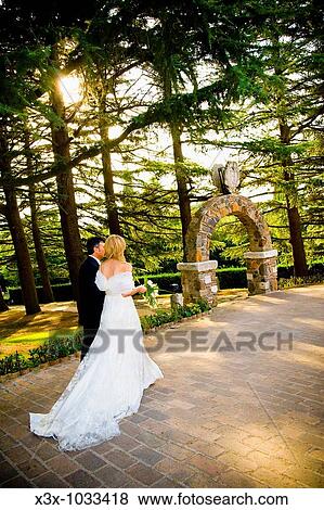 Bride and groom walking hand in hand in a park View Large Photo Image Stock Photo - Bride and groom walking hand in hand in a park. Fotosearch