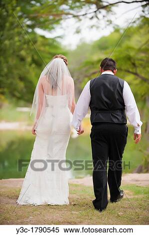 Bride and groom walking hand in hand in natural environment at their wedding View Large Photo Image Stock Photography - Bride and groom walking hand in hand in natural environment at their wedding. Fotosearch