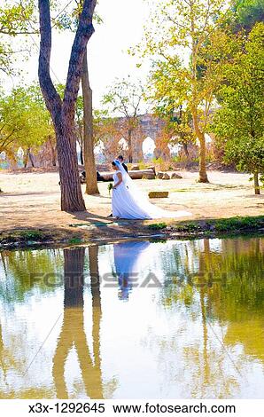 Stock Photography - Bride and groom walking together in a park. Fotosearch