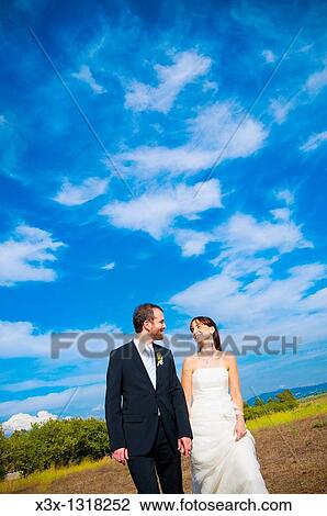 Bride and groom walking together under blue sky View Large Photo Image Stock Image - Bride and groom walking together under blue sky. Fotosearch