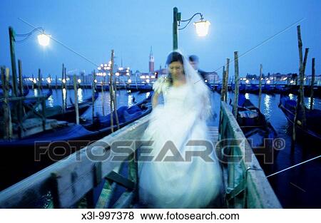 Bride and groom with gondolas at San Marco Pier and San Giorgio Maggiore in background Venice Veneto, Italy View Large Photo Image Stock Photo - Bride and groom with gondolas at San Marco Pier and San Giorgio Maggiore in background Venice Veneto, Italy. Fotosearch