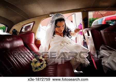 Bride entering the wedding car View Large Photo Image Stock Photo - Bride entering the wedding car. Fotosearch