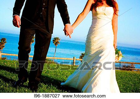 bride & groom excitedly holding hands on way to reception @ gorgeous ocean resort on a sunny beach day View Large Photo Image Stock Photo - bride & groom excitedly holding hands on way to reception @ gorgeous ocean resort on a sunny beach day. Fotosearch