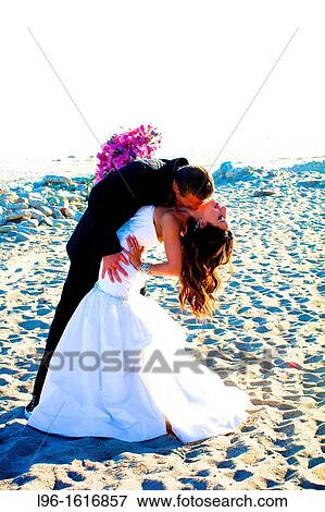 bride groom kissing embracing on beach after wedding holding boquet View Large Photo Image Stock Photo - bride groom kissing embracing on beach after wedding holding boquet. Fotosearch