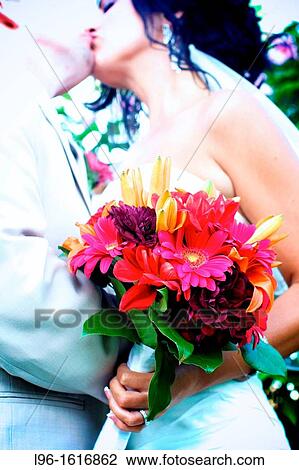 Stock Image - bride groom kissing embracing with bouquet after wedding. Fotosearch