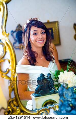 Bride holding the wedding bouquet and looking at herslef in the mirror View Large Photo Image Picture - Bride holding the wedding bouquet and looking at herslef in the mirror. Fotosearch