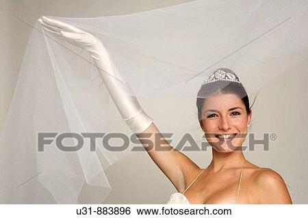 Bride in her 20s discovers herself from under her veil View Large Photo Image Stock Photograph - Bride in her 20s discovers herself from under her veil. Fotosearch