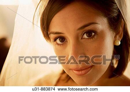 Picture - Bride in her 20s looks at the camera during make up. Fotosearch