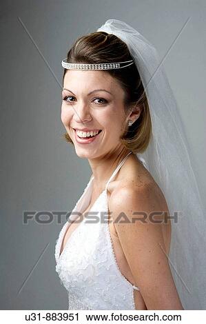 Stock Image - Bride in her 20s smiles at the camera in a studio setting. Fotosearch