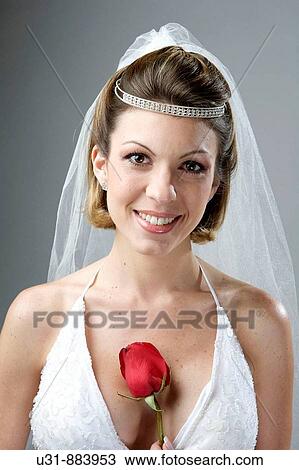 Bride in her 20s smiles at the camera in a studio setting with a red rose View Large Photo Image Stock Image - Bride in her 20s smiles at the camera in a studio setting with a red rose. Fotosearch