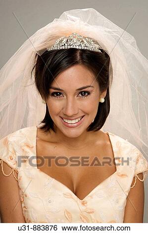 Stock Photograph - Bride in her 20s smiles at the camera in a studio setting. Fotosearch