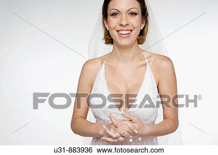 Stock Photograph - Bride in her 20s smiles at the camera in a studio setting. Fotosearch