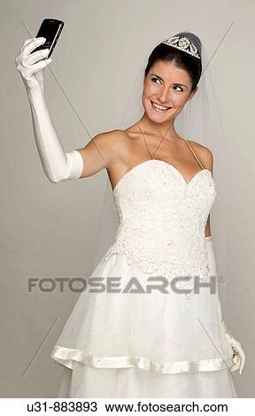 Bride in her 20s takes a picture of herself with her cell phone View Large Photo Image Stock Image - Bride in her 20s takes a picture of herself with her cell phone. Fotosearch