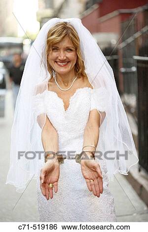 Stock Photograph - Bride in wedding dress in handcuffs on street. Fotosearch