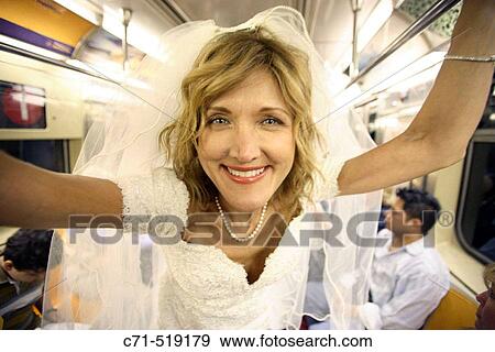 Bride in wedding dress in subway car smiling in camera View Large Photo Image Stock Photo - Bride in wedding dress in subway car smiling in camera. Fotosearch