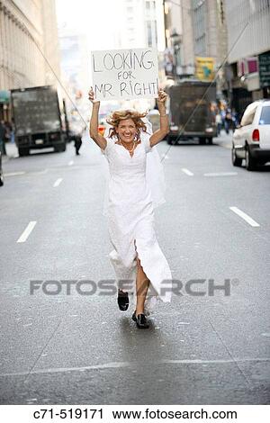 Bride in wedding dress running Downtreet holding a sign overhead reading? Looking for Mr. Right? View Large Photo Image Stock Image - Bride in wedding dress running Downtreet holding a sign overhead reading? Looking for Mr. Right?. Fotosearch