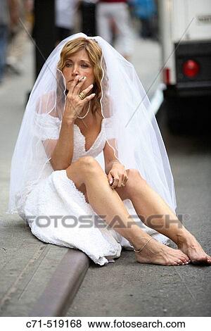 Bride in wedding dress siting on the curb smoking a cigarette View Large Photo Image Stock Photo - Bride in wedding dress siting on the curb smoking a cigarette. Fotosearch