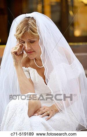 Stock Photo - Bride in wedding dress sitting on steps crying. Fotosearch