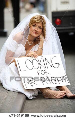 Bride in wedding dress sitting on the curb holding a sign saying? Looking for Mr. Right? View Large Photo Image Stock Photo - Bride in wedding dress sitting on the curb holding a sign saying? Looking for Mr. Right?. Fotosearch