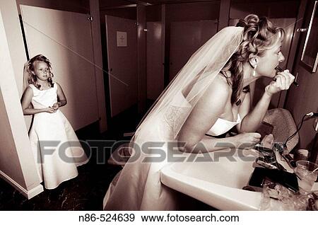 Bride preparing in bathroom with flower girl View Large Photo Image Stock Photo - Bride preparing in bathroom with flower girl. Fotosearch