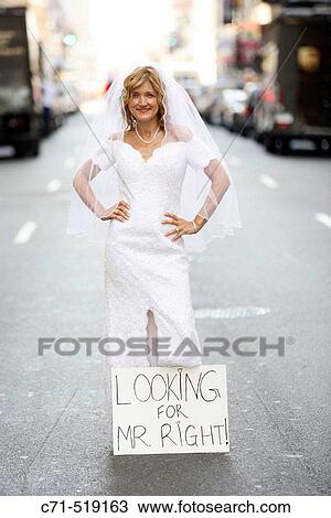 Bride standing in middle of street wearing wedding dress with? Looking for Mr. Right? sign at feet View Large Photo Image Stock Image - Bride standing in middle of street wearing wedding dress with? Looking for Mr. Right? sign at feet. Fotosearch