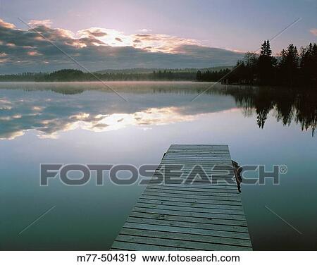 Stock Photo - Bridge in the lake, summer morning, fog, water, calm lake. Lake Grecken. V? stmanland. Sweden. Fotosearch