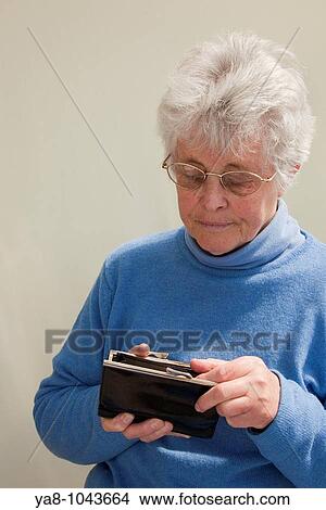 Britain UK Europe Senior woman looking into a purse with concerned expression MR 09/05 View Large Photo Image Picture - Britain UK Europe Senior woman looking into a purse with concerned expression MR 09/05. Fotosearch