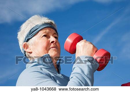 Stock Photo - Britain, UK, Europe Senior woman exercising with dumbbell hand weights outdoors MR 10/02. Fotosearch