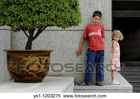 Stock Photography - Brother and his young sister leaning against a wall in Xi? an, Shaanxi, China.. Fotosearch