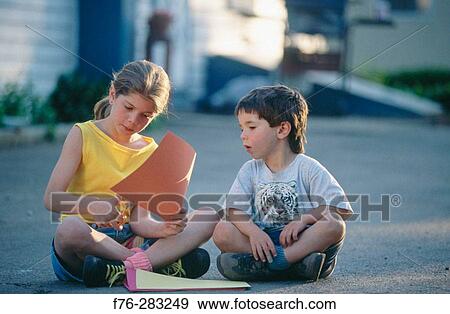 Stock Photo - Brother and sister cutting out paper pumpkins together. Fotosearch