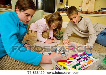 Brother and sisters sitting on rug in basement playroom and drawing in sketchbooks with colored markers and crayons View Large Photo Image Stock Photo - Brother and sisters sitting on rug in basement playroom and drawing in sketchbooks with colored markers and crayons. Fotosearch