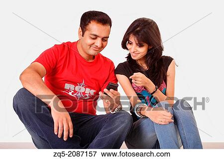 Stock Photo - Brother sharing something on mobile with his sister, Pune, India.. Fotosearch