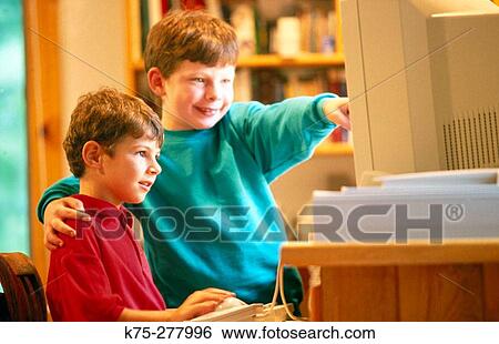 Stock Photograph - Brothers using computer together. Fotosearch