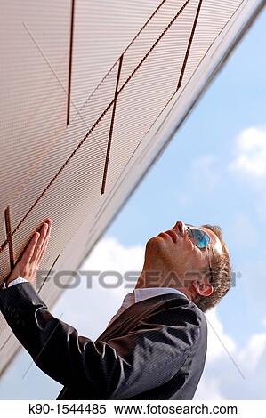 Brown haired young man with sunglasses, looking up into the air, supporting himself by with one hand at the wall, blue skyl, Hamburg, Germany, Europe View Large Photo Image Stock Photography - Brown haired young man with sunglasses, looking up into the air, supporting himself by with one hand at the wall, blue skyl, Hamburg, Germany, Europe. Fotosearch