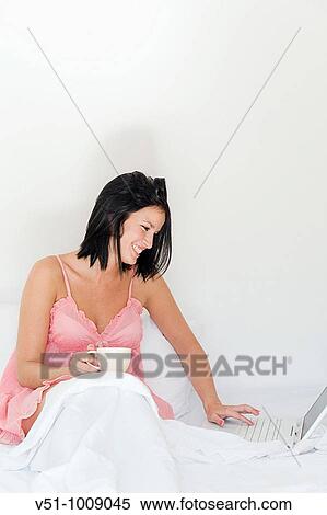 Bruentte woman enjoying breakfast in bed smiling with laptop View Large Photo Image Stock Photography - Bruentte woman enjoying breakfast in bed smiling with laptop. Fotosearch
