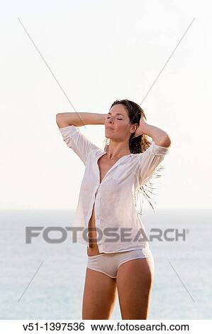 Stock Photograph - Brunette beautiful woman stretching by the sea. Fotosearch