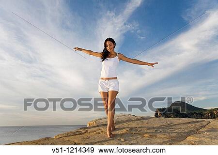 Stock Photo - Brunette palyful woman in a cliff in Ibiza, Balearic Islands. Fotosearch