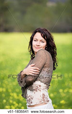 Stock Image - Brunette pretty woman in countryside looking at camera. Fotosearch