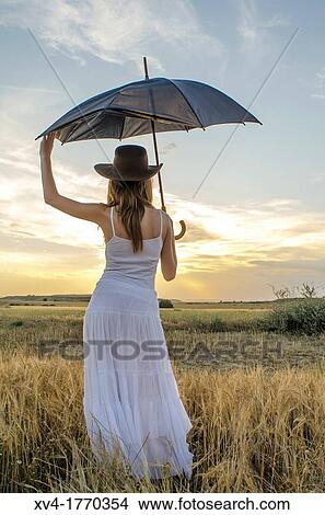 Brunette relaxing in the countryside look at horizont with umbrella View Large Photo Image Picture - Brunette relaxing in the countryside look at horizont with umbrella. Fotosearch